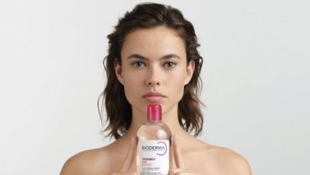 Mujer sonriendo mostrando producto de agua micelar Mujer sonriendo mostrando producto de agua micelar