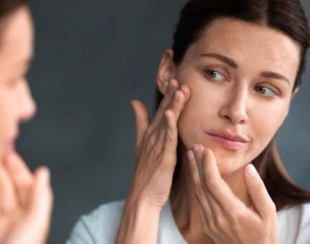 Mujer revisando el acné en su rostro 